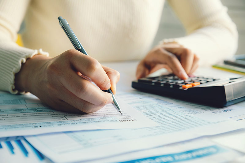 Close up of homeowner doing taxes with calculator 